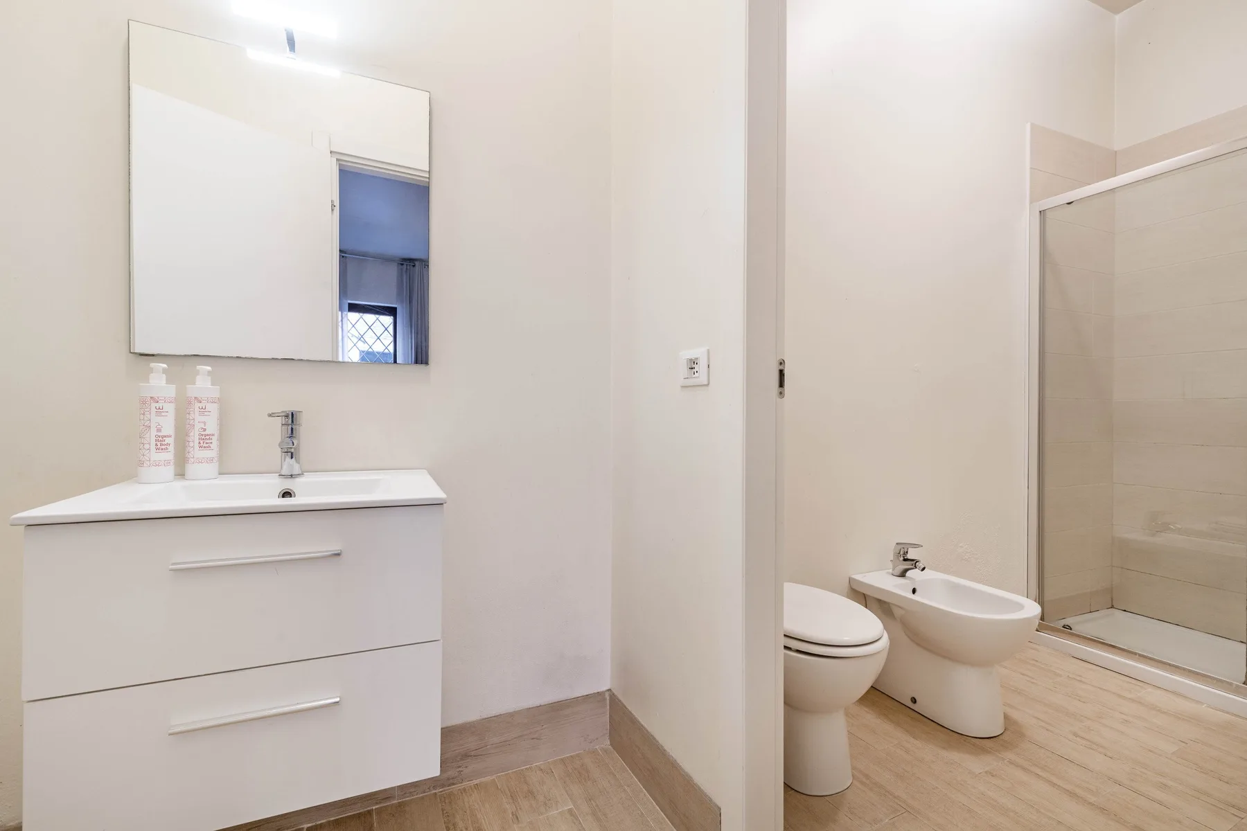 Un baño luminoso con lavabo, inodoro, bidé y ducha de vidrio.