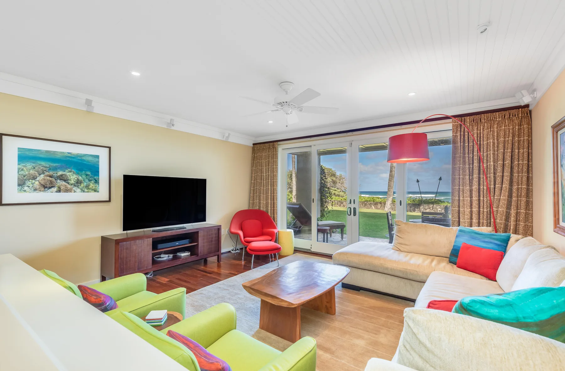 A bright living room with seating, a coffee table, and glass doors opening onto a patio.