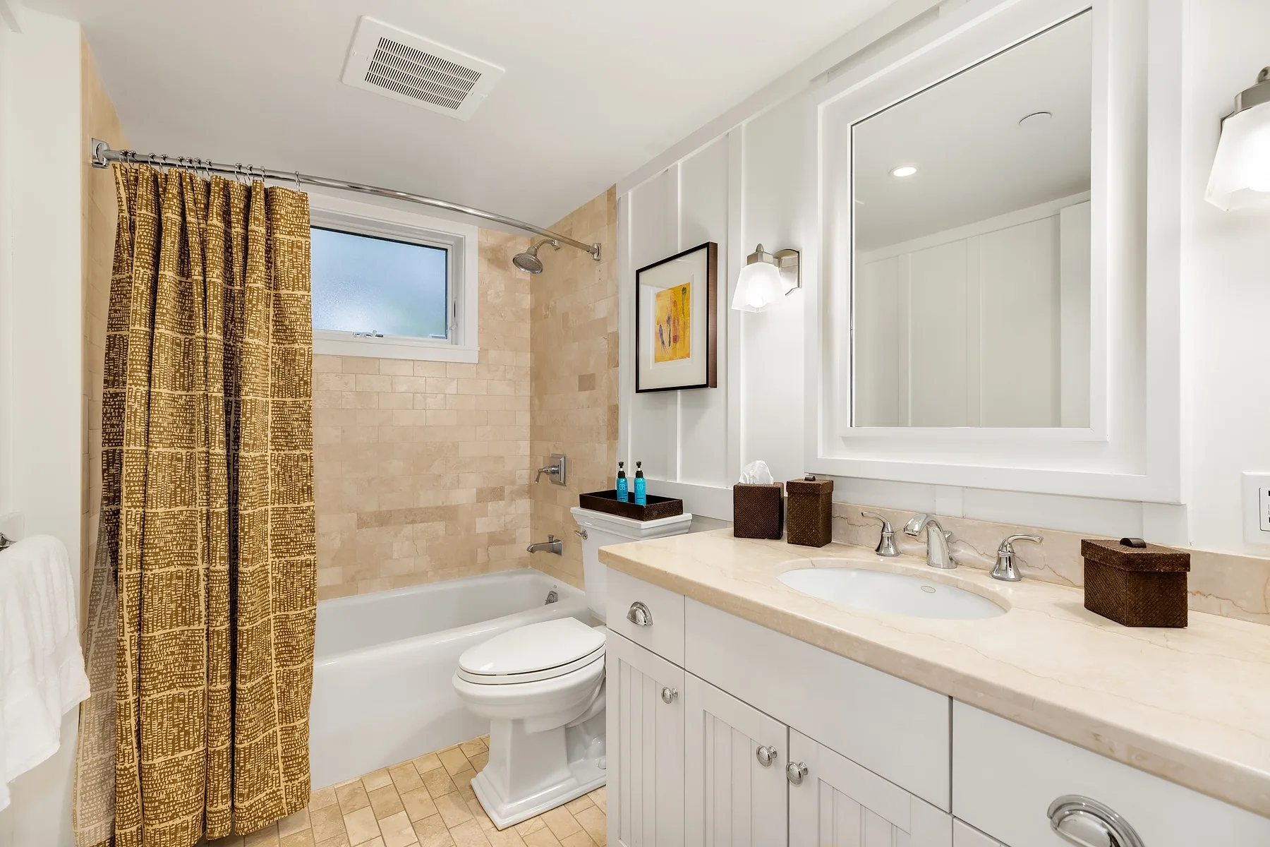 A bright bathroom with a bathtub, shower curtain, and long vanity.