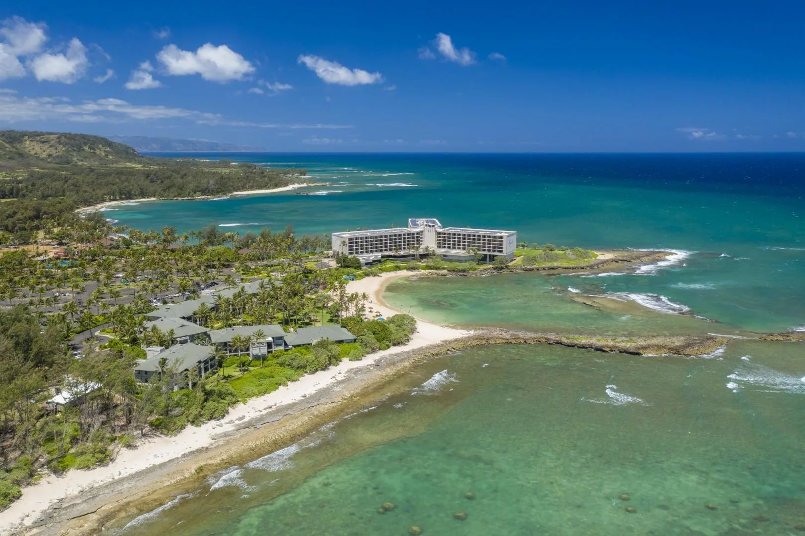 Aerial coastal view of a resort beside a turquoise lagoon and open ocean.