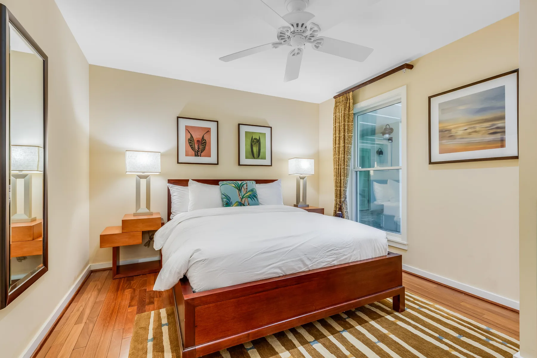 A bedroom with a bed, bedside tables, and framed artwork on the walls.