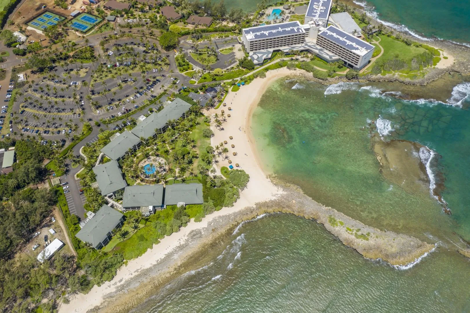 Aerial view of a coastal resort beside a sandy beach and clear water.
