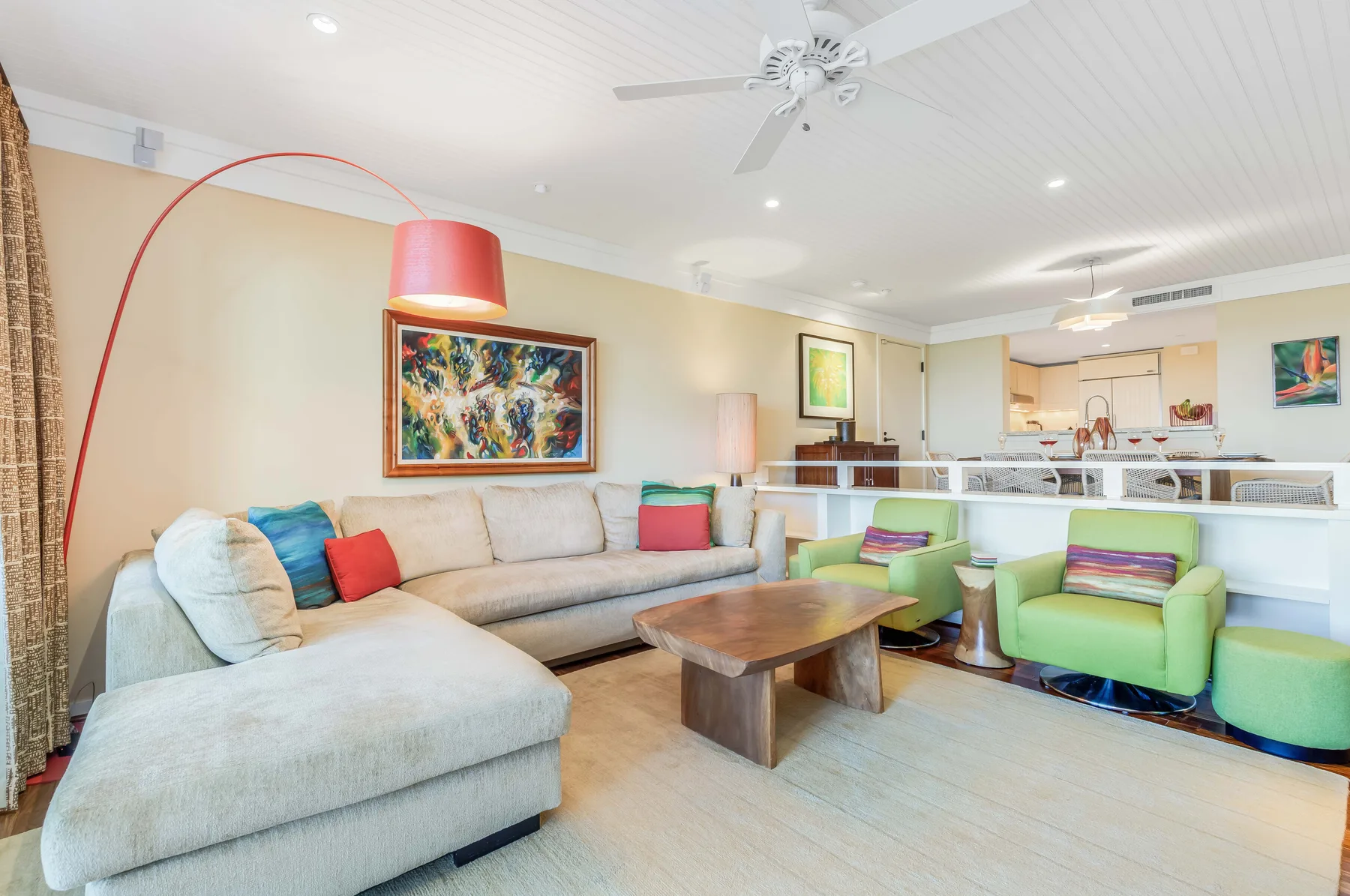 A bright living room with a sectional sofa and colorful armchairs.