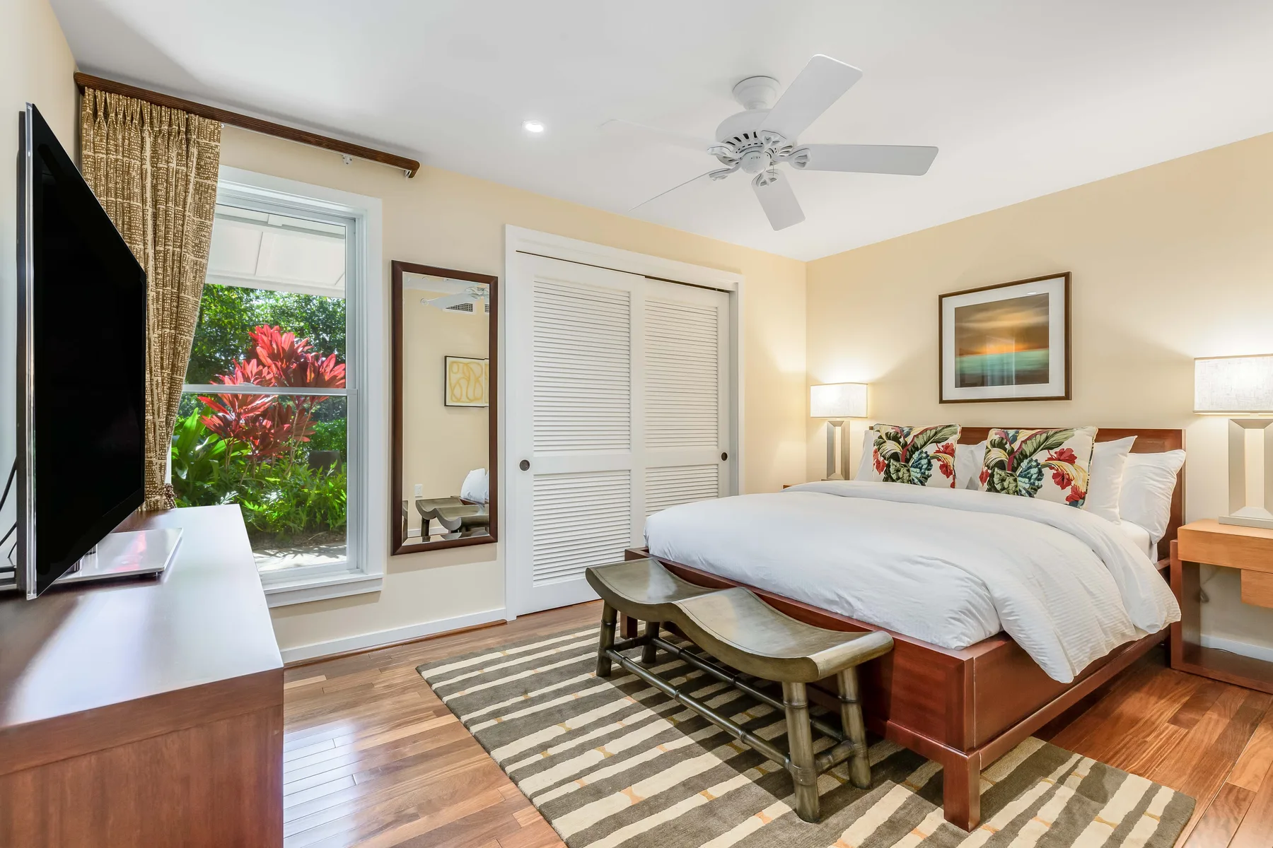 A bedroom with a bed, patterned pillows, and a ceiling fan.