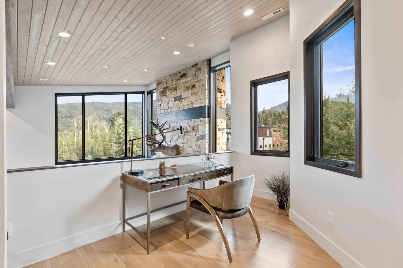 A bright dining area with a table and large windows overlooking greenery.