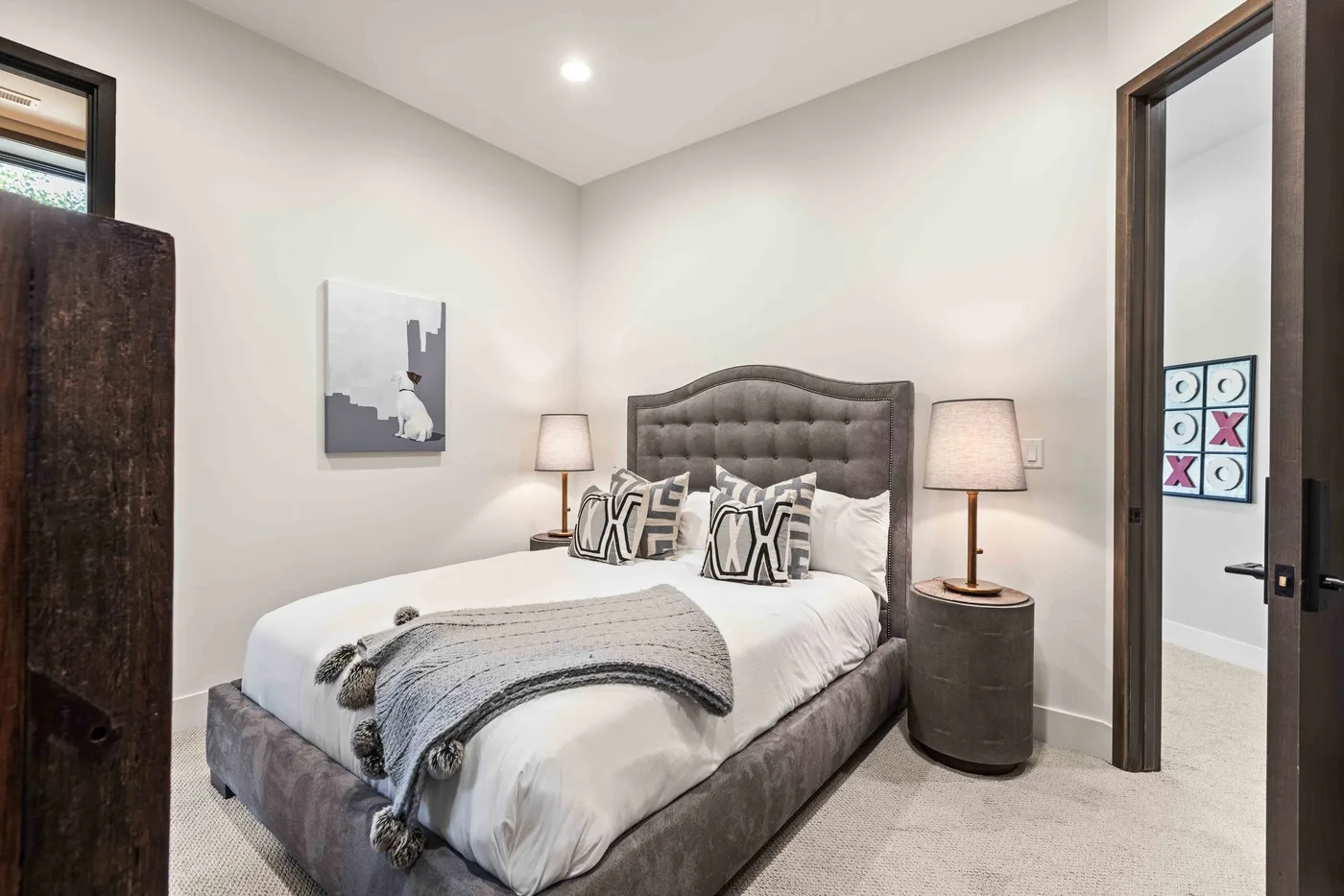 A bedroom with a bed, bedside lamps, and framed wall art.
