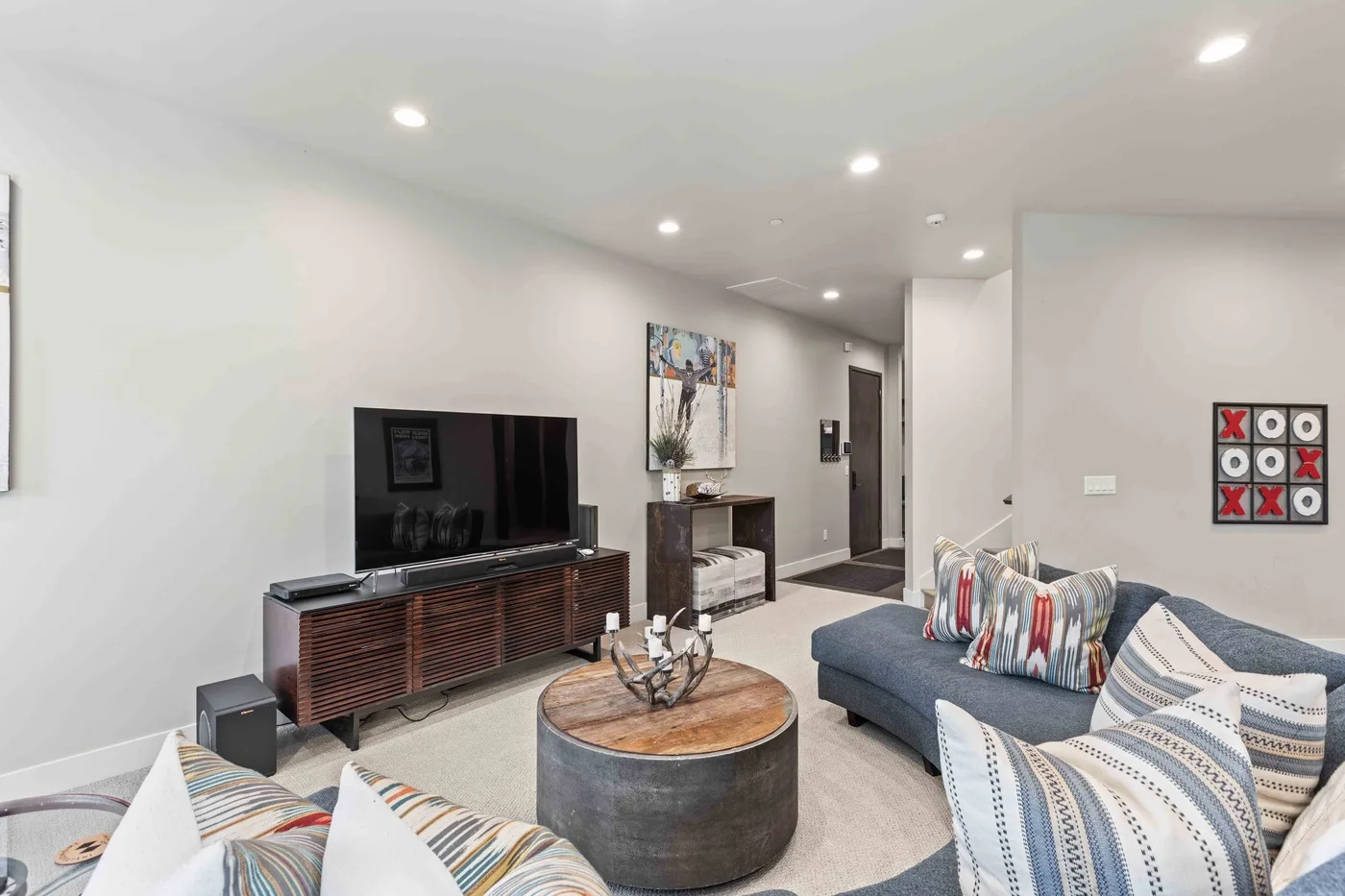 A bright living room with a television, low table, and cushioned seating.