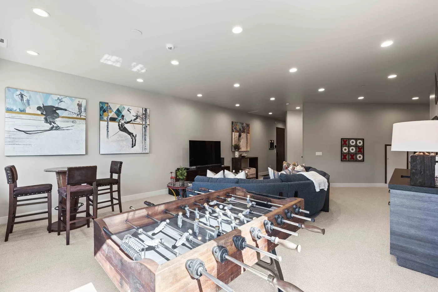 A spacious game room features a foosball table, seating, and wall art.