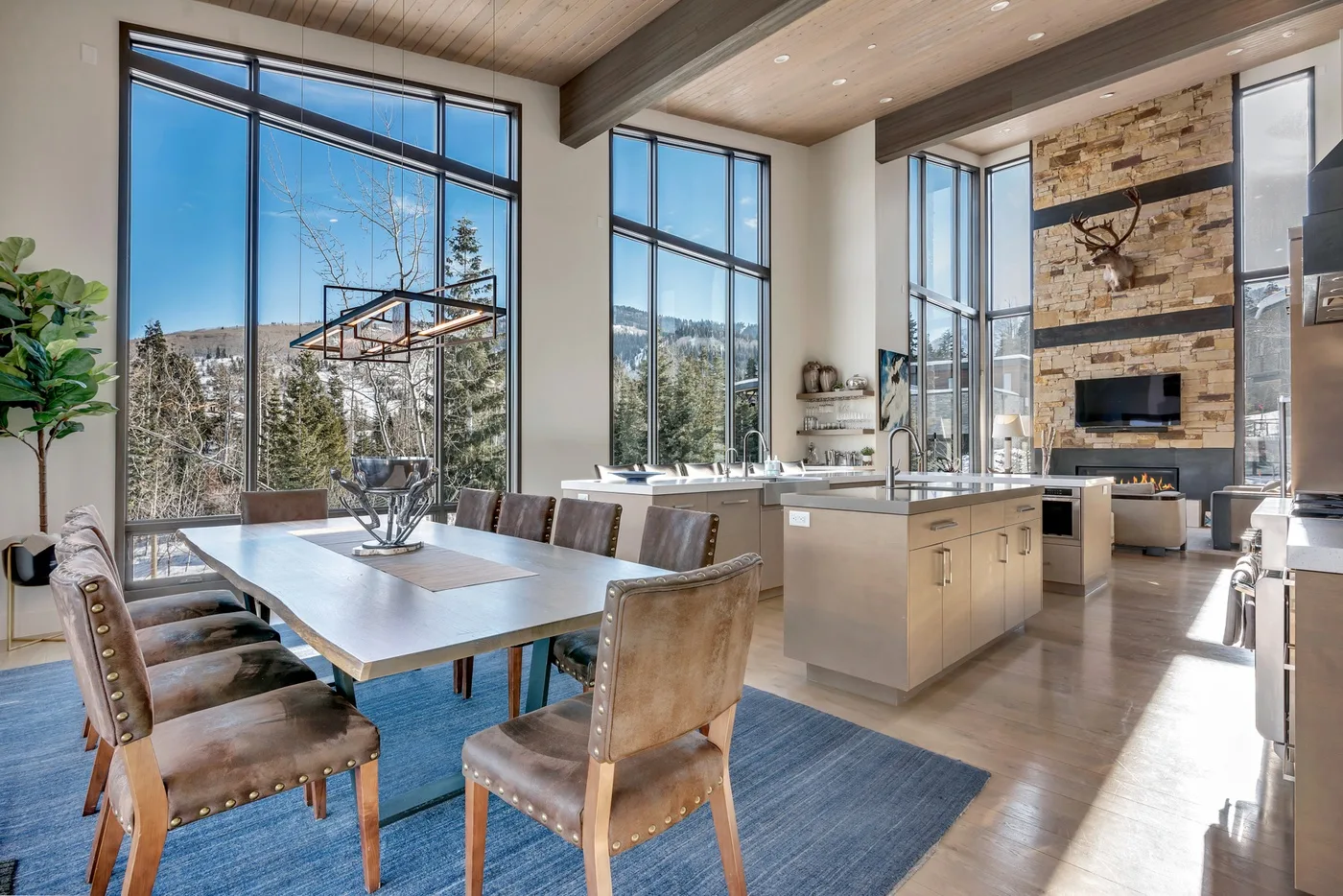 An open dining and kitchen area with a large table and tall windows.