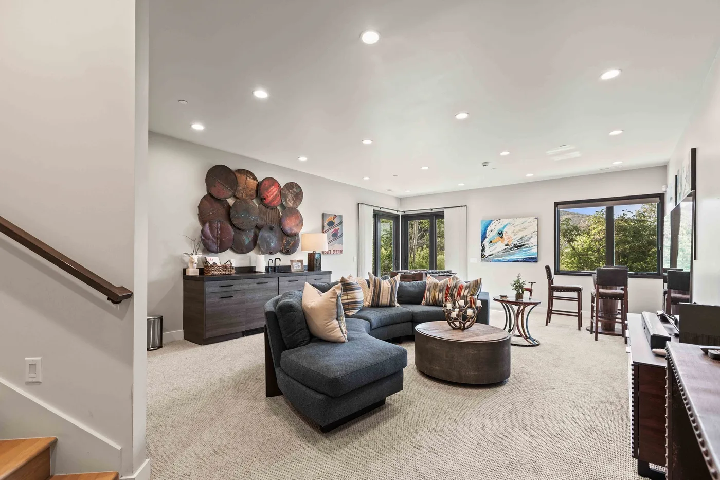 A bright living room with a sectional seating area, coffee table, and large windows.