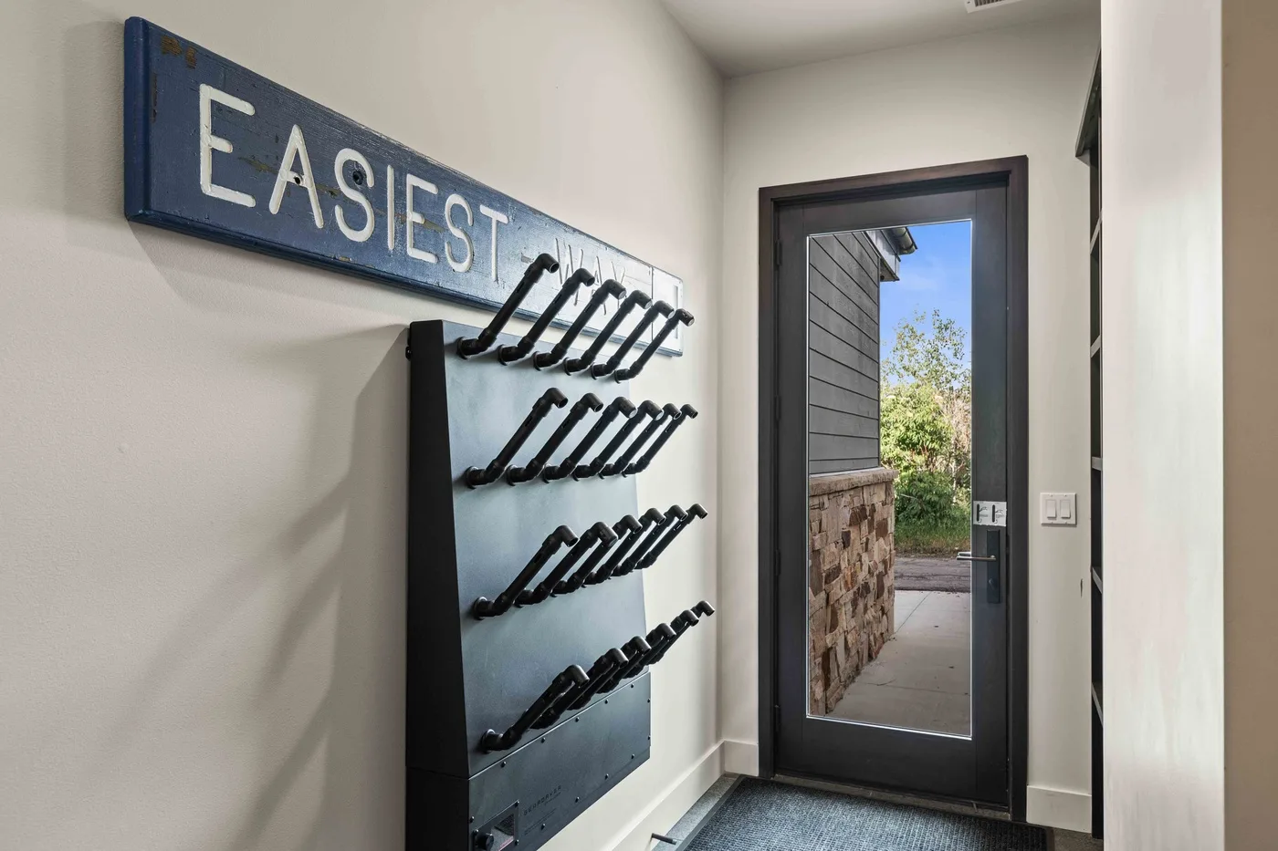 An entryway has a wall-mounted key rack beside a glass door.