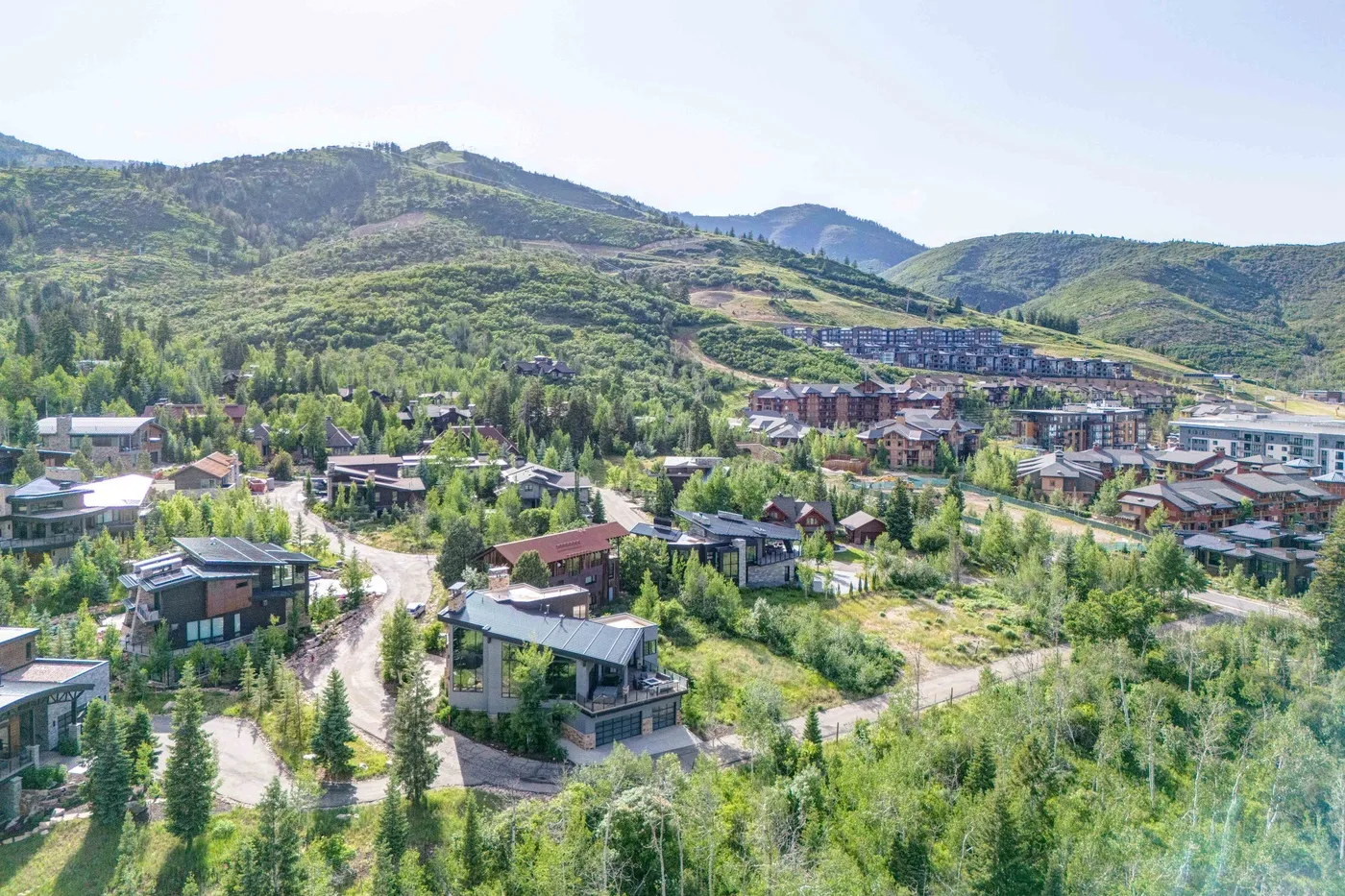 A hillside settlement spreads across a green valley surrounded by mountains.