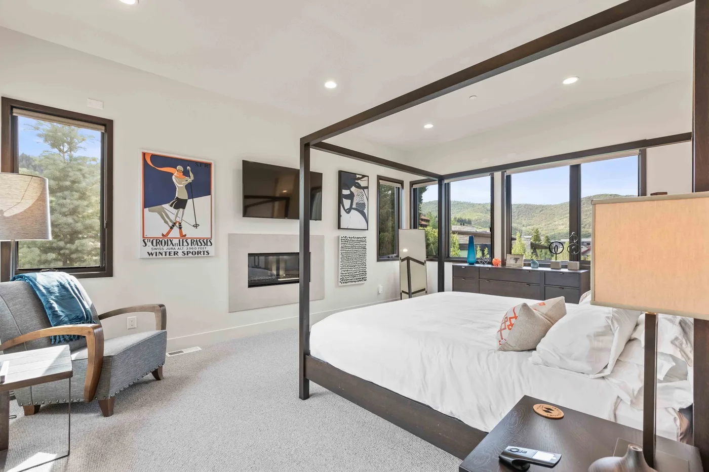 A bright bedroom with a large bed and windows overlooking a green landscape.
