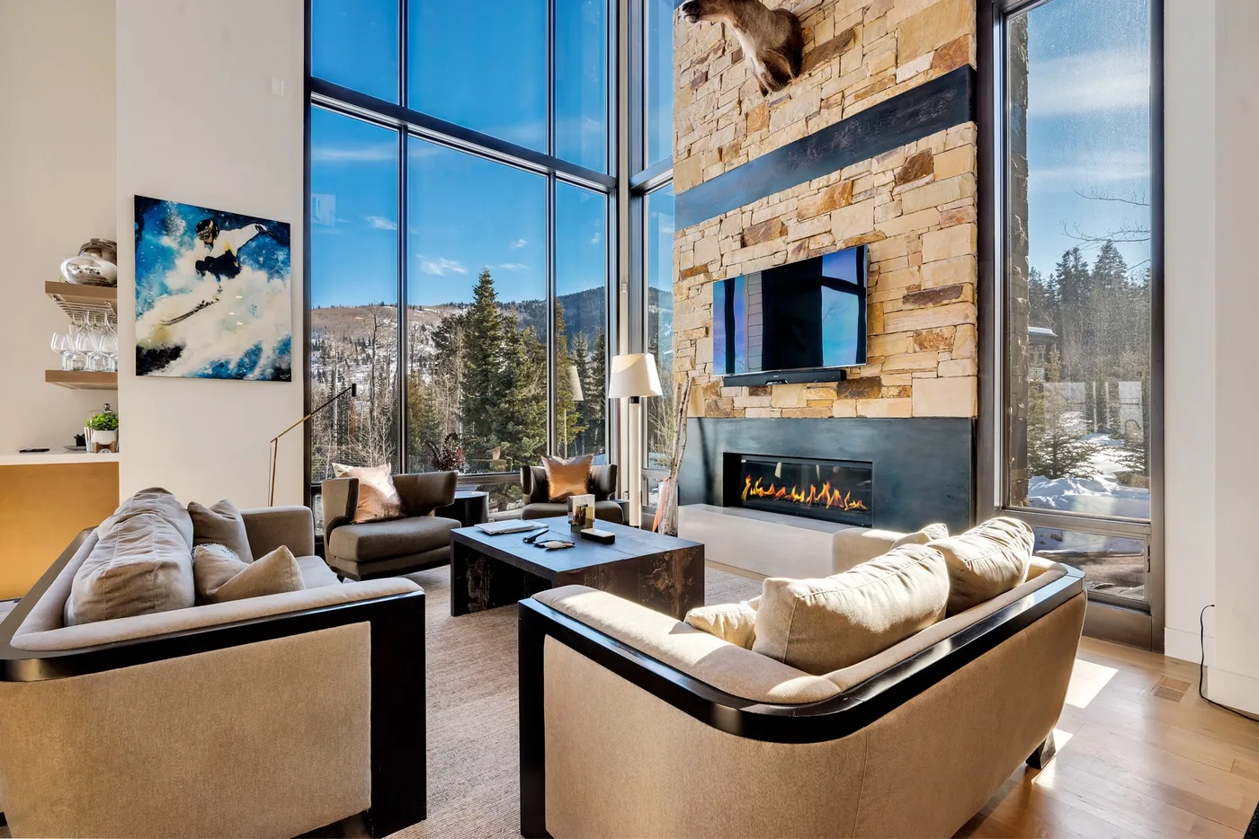 A spacious living room with seating arranged around a low table and a stone fireplace.