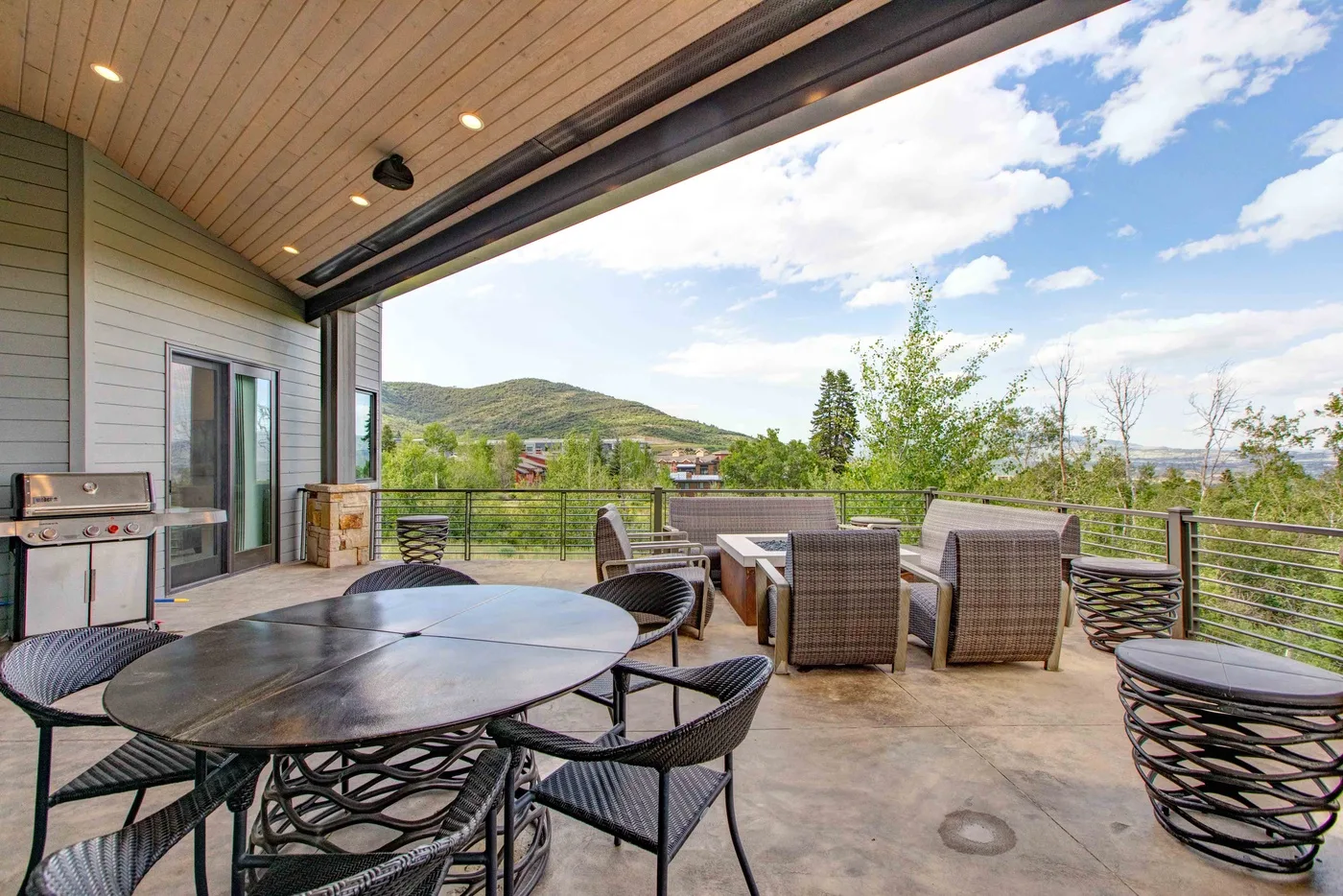 An outdoor dining terrace with table seating and a view of green hills.