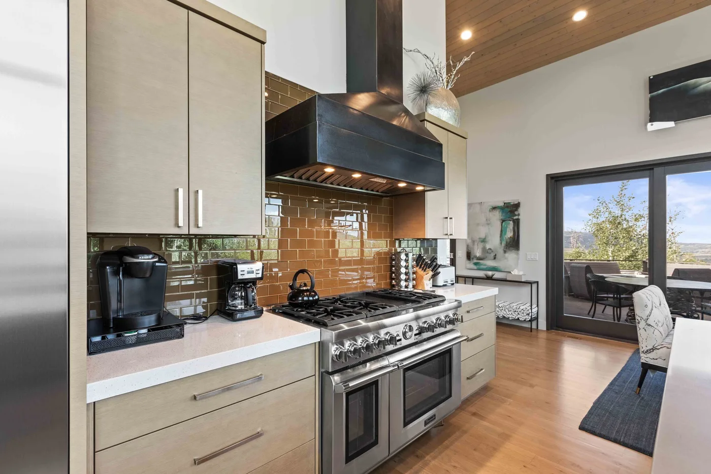 A modern kitchen with a large range and an open dining area by the glass doors.