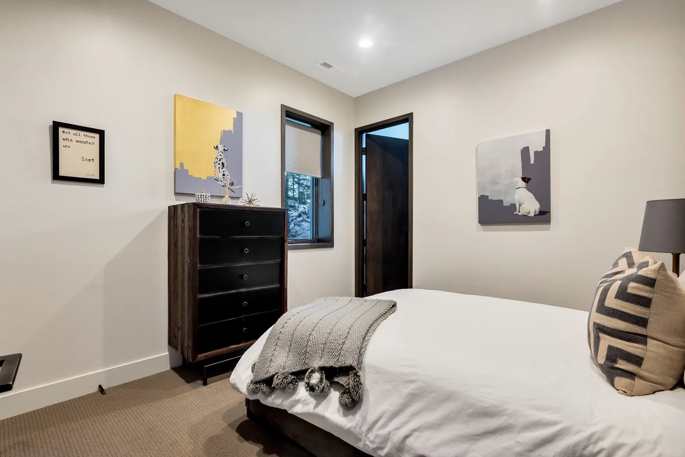 A bedroom with a neatly made bed and a dark dresser.