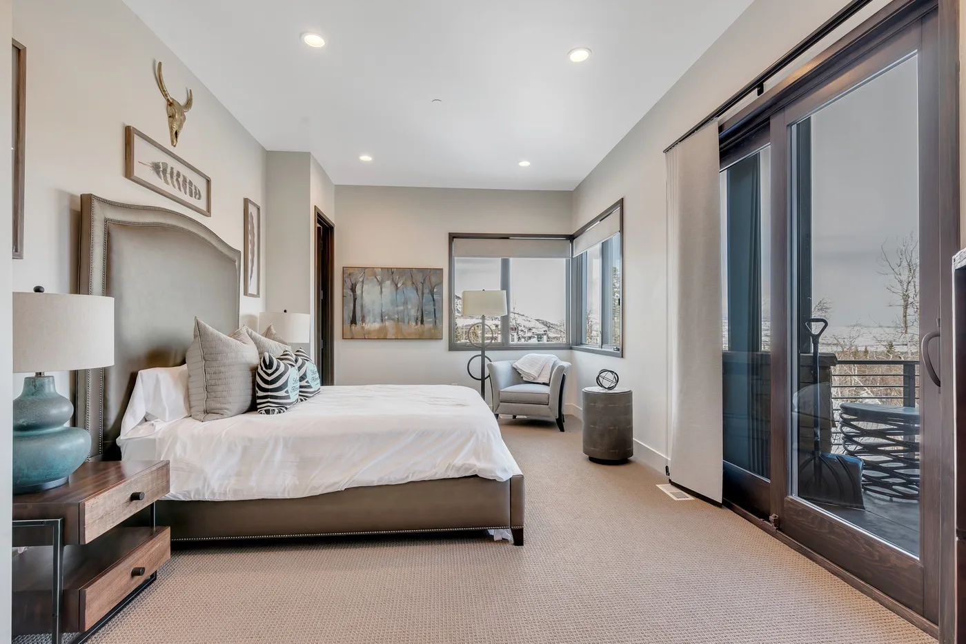 A bright bedroom with a bed, seating area, and large windows.