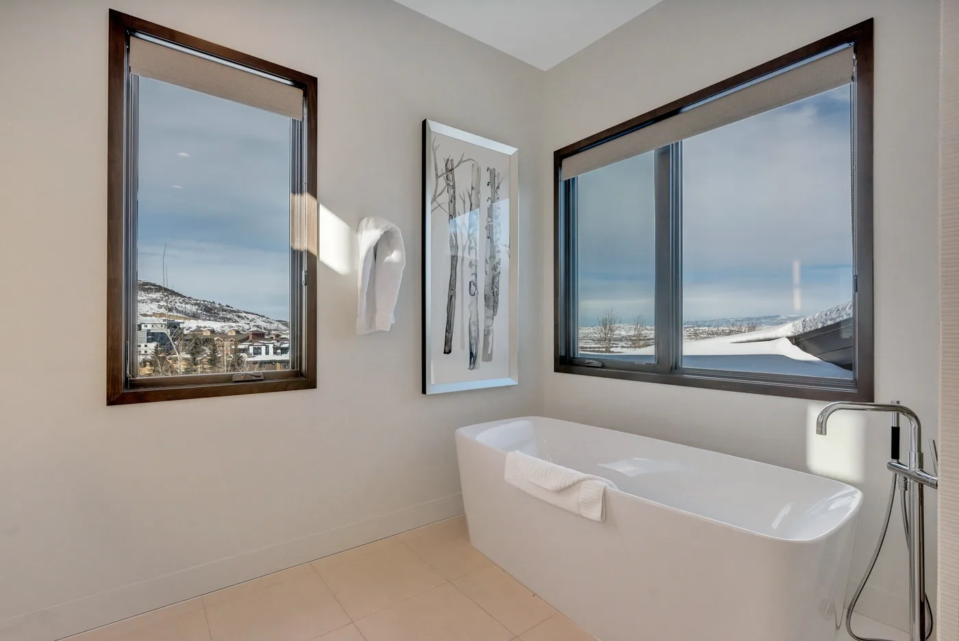 A bathroom with a bathtub beside large windows overlooking a snowy landscape.