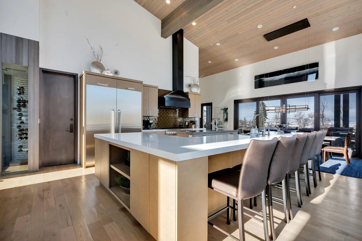 A modern kitchen with a large island and seating opens onto a dining area.