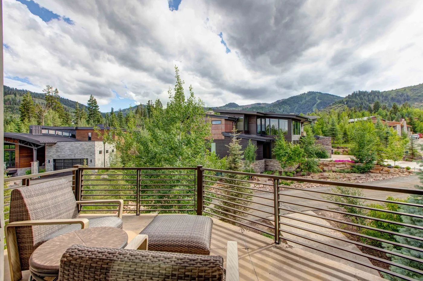 A wooden outdoor deck overlooks modern buildings and a green mountain landscape.