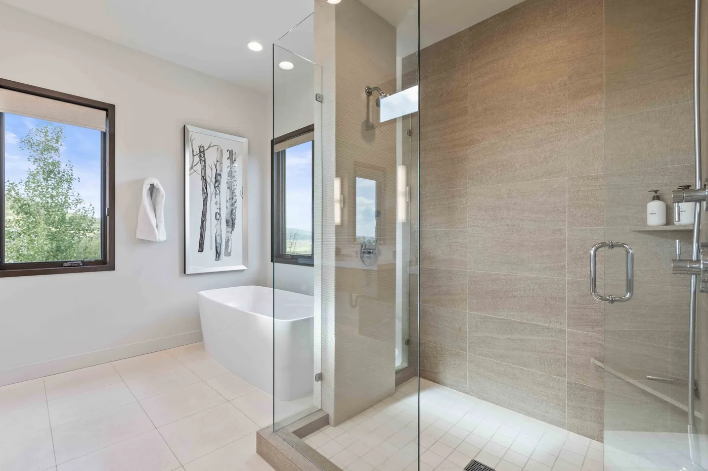 A bright bathroom with a bathtub beside a glass-enclosed shower.
