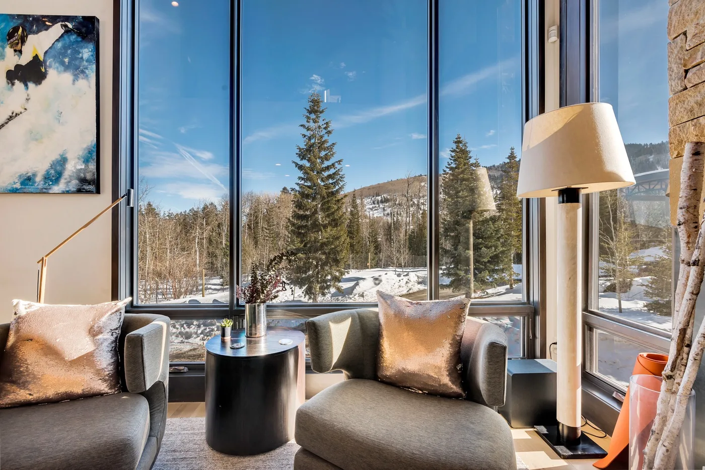 A bright living room with seating beside large windows overlooking a snowy landscape.