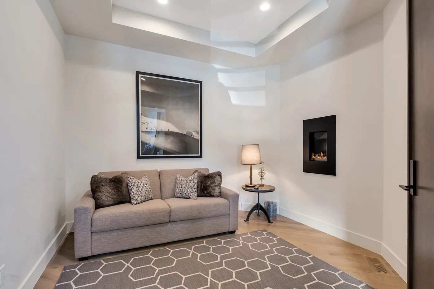 A sitting area with a sofa, framed artwork, and a geometric rug.