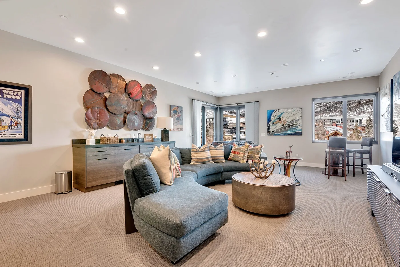 A bright living room with a curved sectional and a round coffee table.