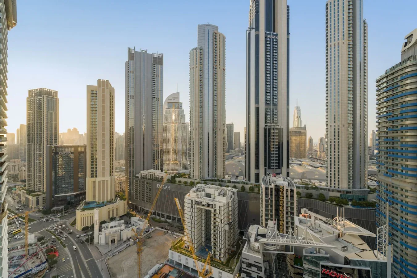 A city skyline of tall modern buildings rises above roads and construction sites.