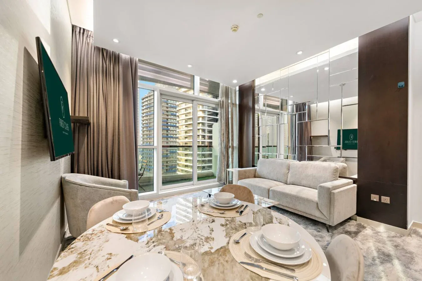 A modern living and dining area with a sofa, set table, and large windows.