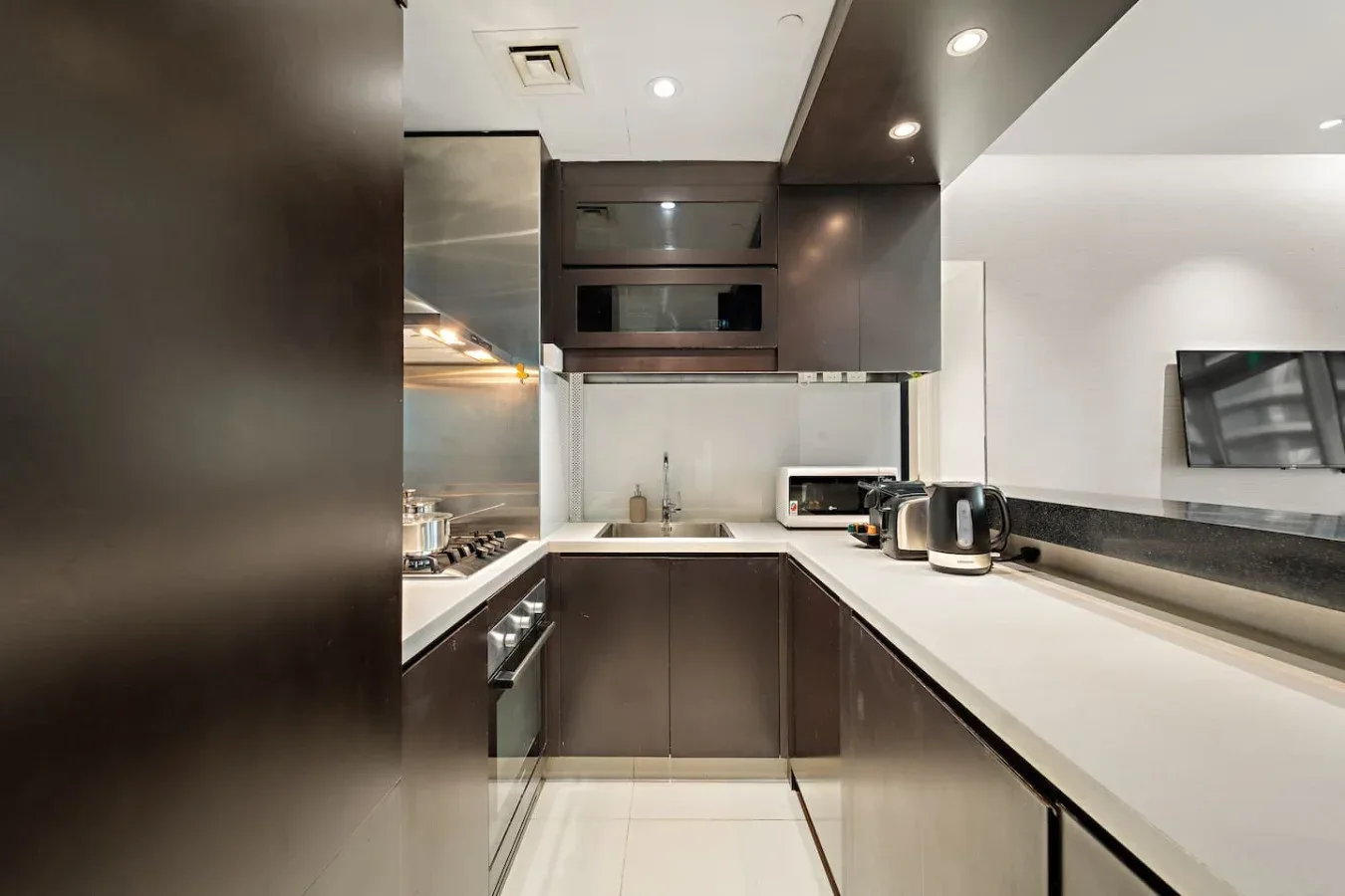 A modern kitchen with dark cabinetry and a long light-colored countertop.