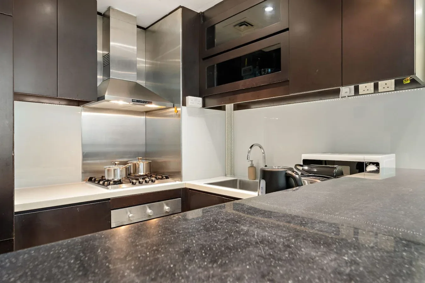 A modern kitchen with dark cabinets, a cooktop, and a countertop.