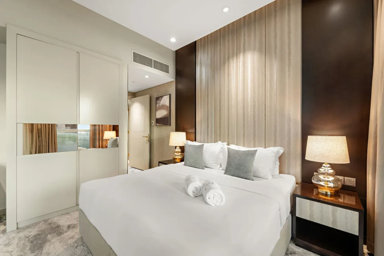 A bright bedroom with a neatly made bed and soft gray accents.