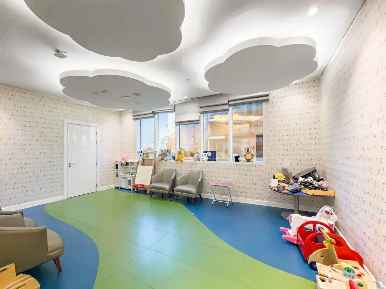 A colorful children's playroom has patterned walls, window seating, and toys.