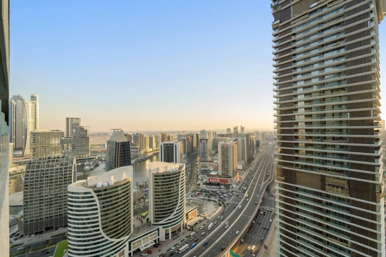 A city skyline with high-rise buildings and a busy multilane road.