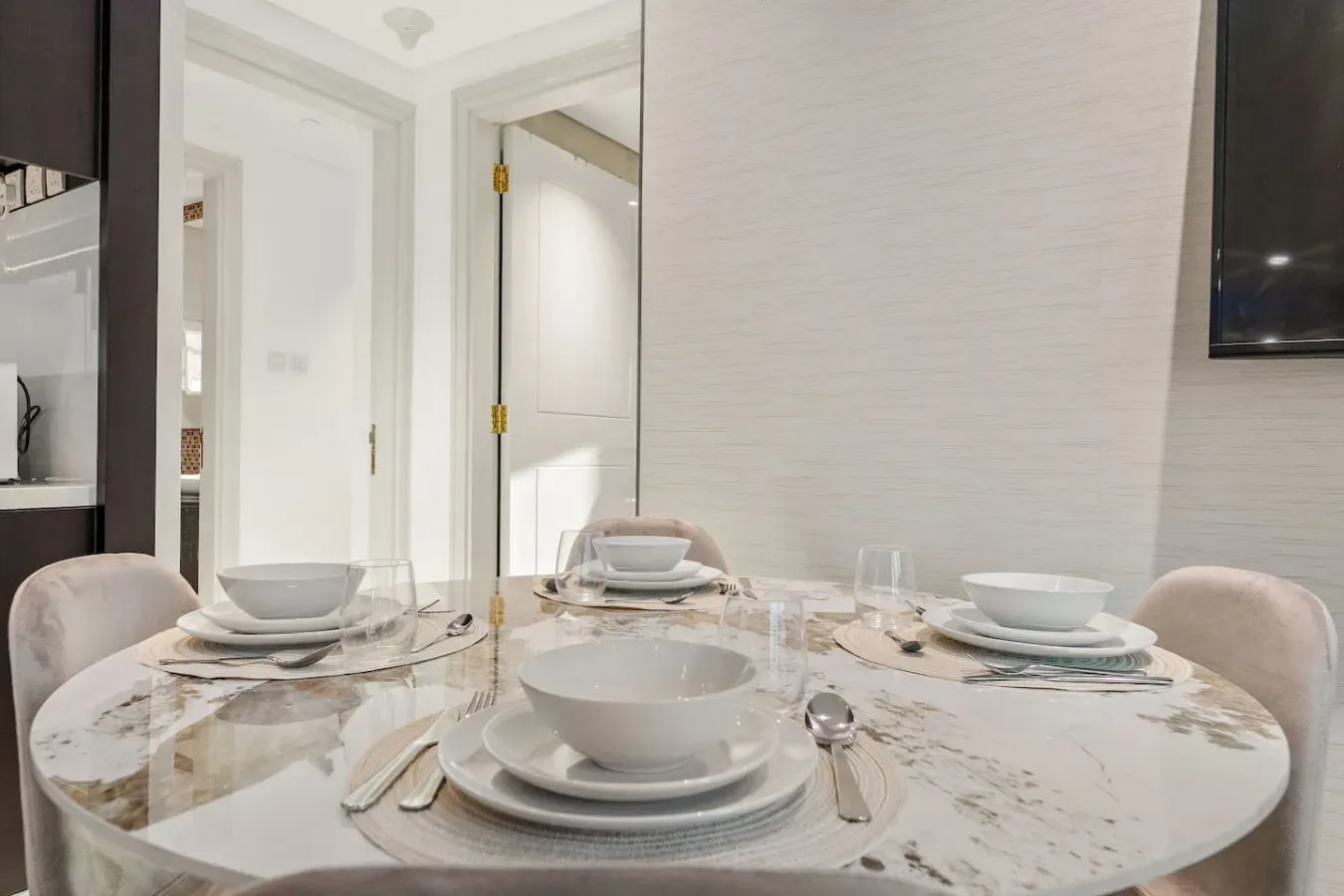 A dining area with a round table set with plates and bowls.