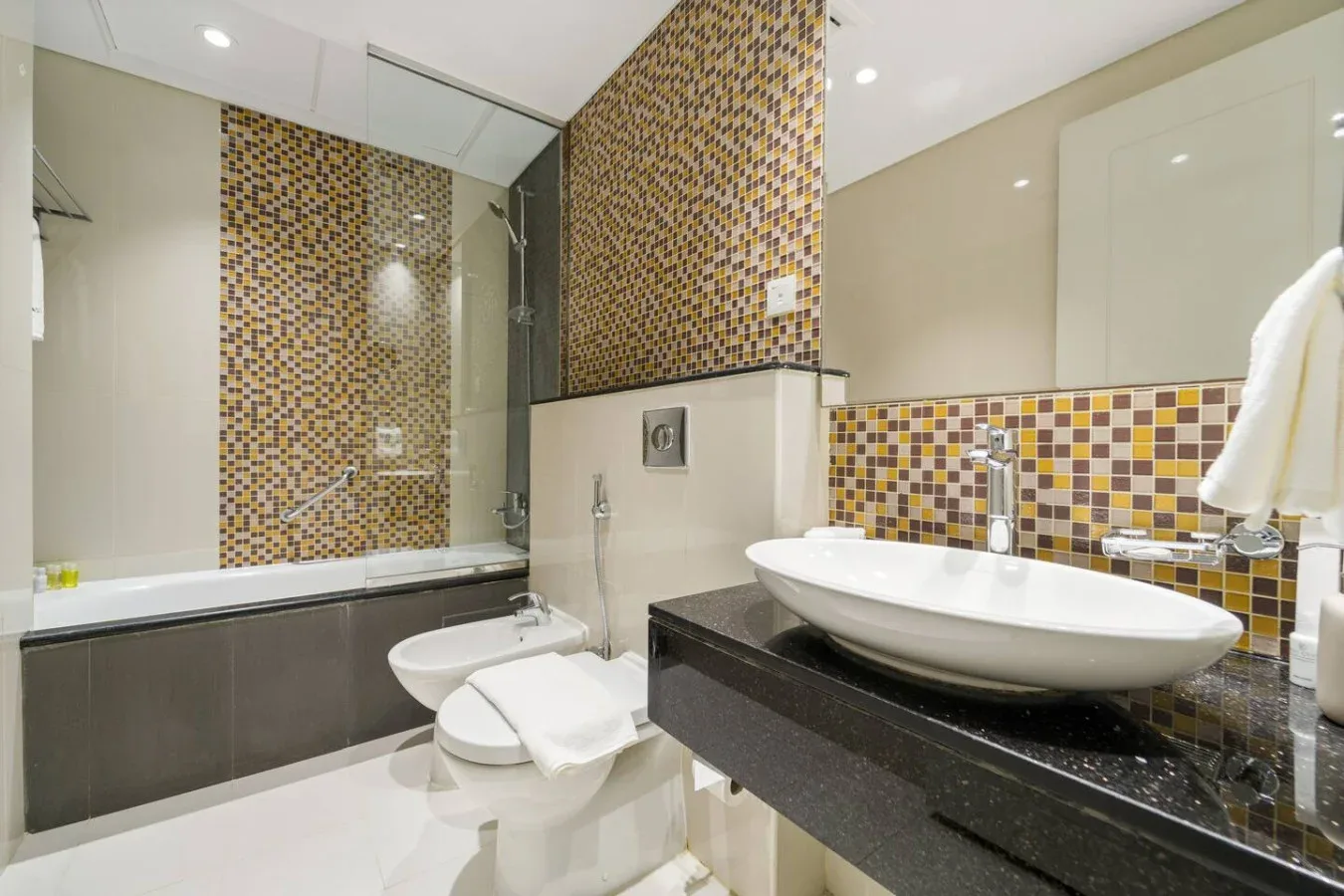 A tiled bathroom with a bathtub, toilet, and sink.