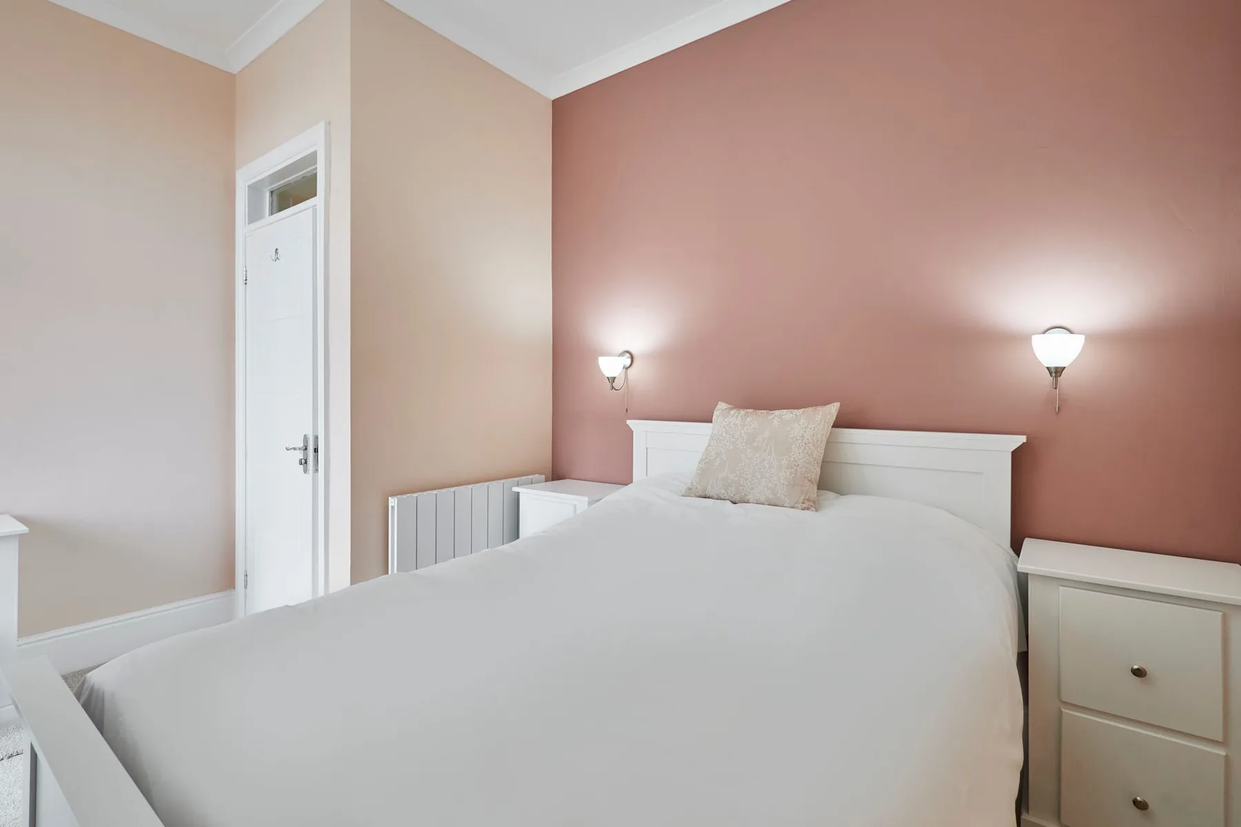Un dormitorio con una cama, una mesita de noche y luces de pared.