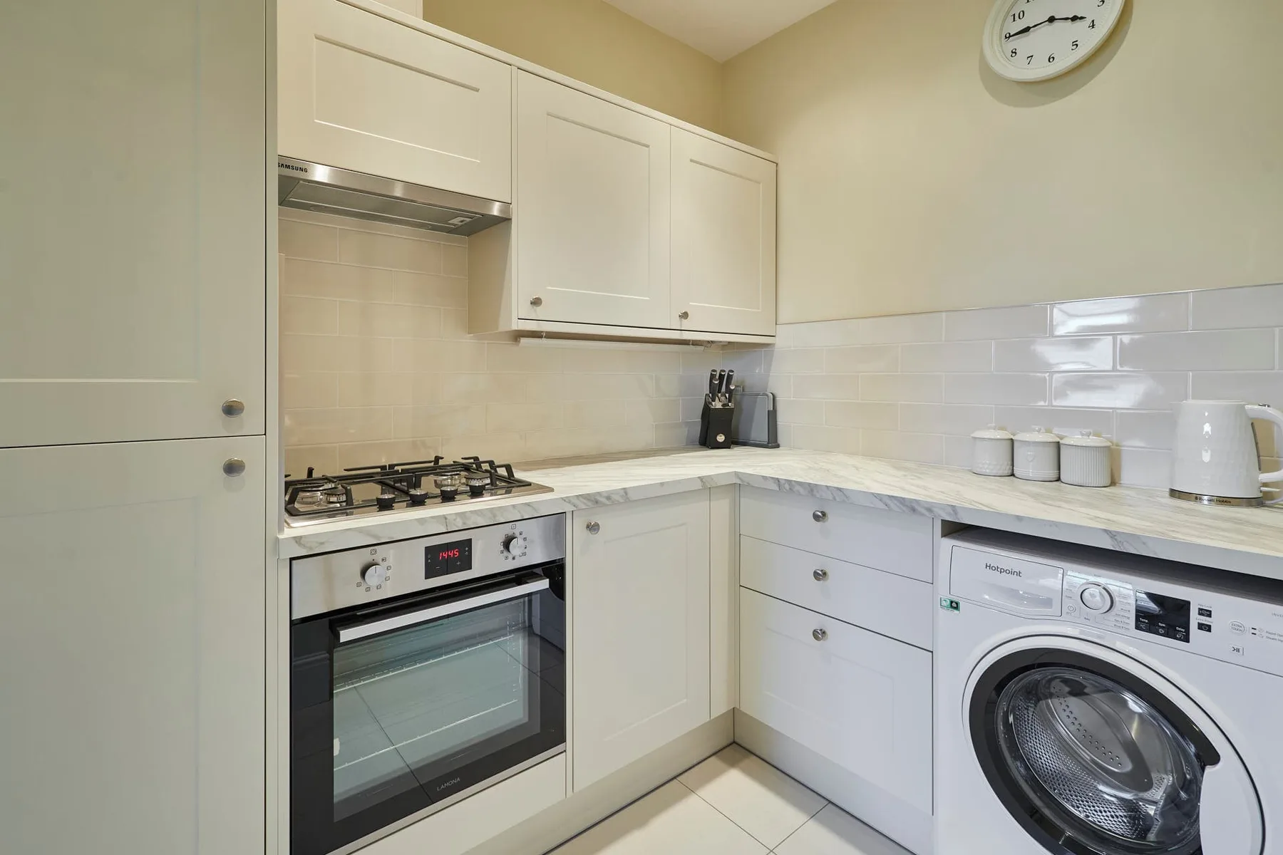 Una cocina luminosa con gabinetes blancos, una estufa y una lavadora.