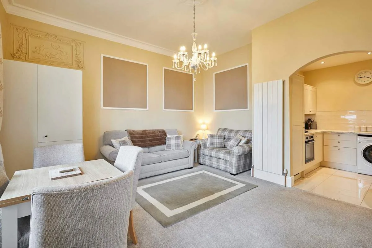 A living room with seating, a rug, and an open archway to the kitchen.