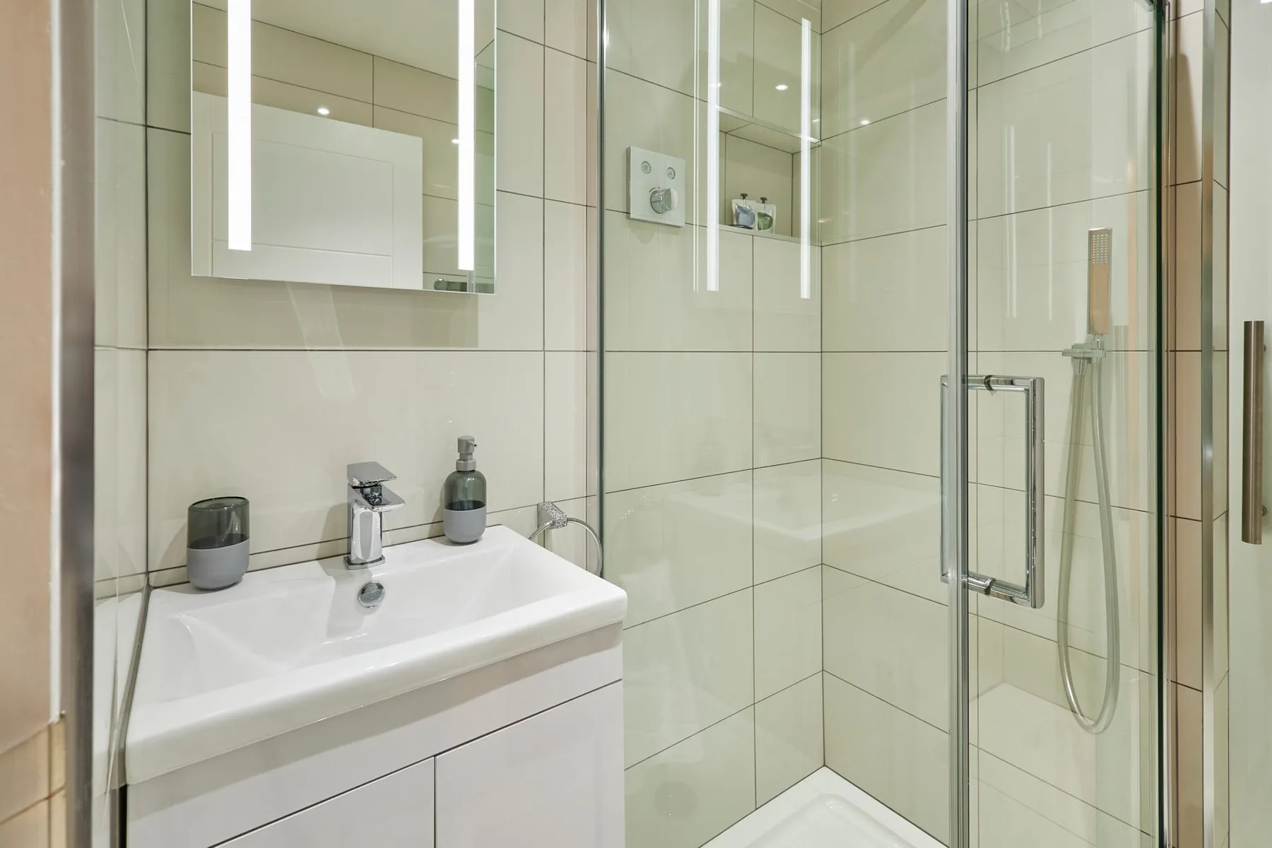 A tiled bathroom with a sink, mirror, and glass shower.