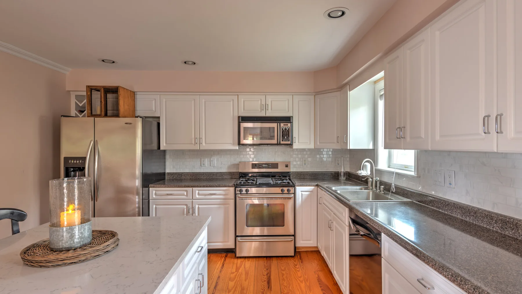 A bright kitchen with white cabinets, stainless steel appliances, and a central island.