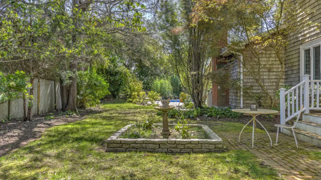 A landscaped backyard garden with a stone-edged planting bed beside a house.