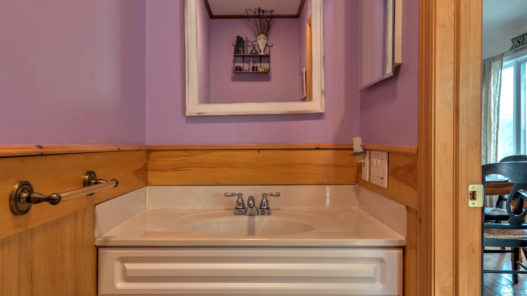 A bathroom vanity with a sink sits beneath a framed mirror.