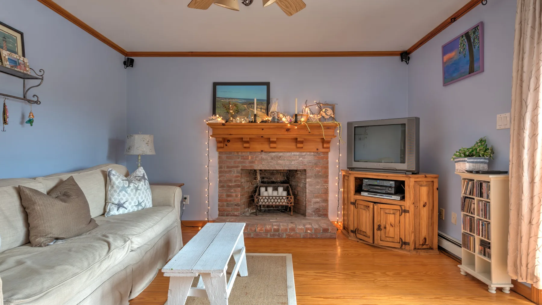 A living room with seating, a brick fireplace, and a television.
