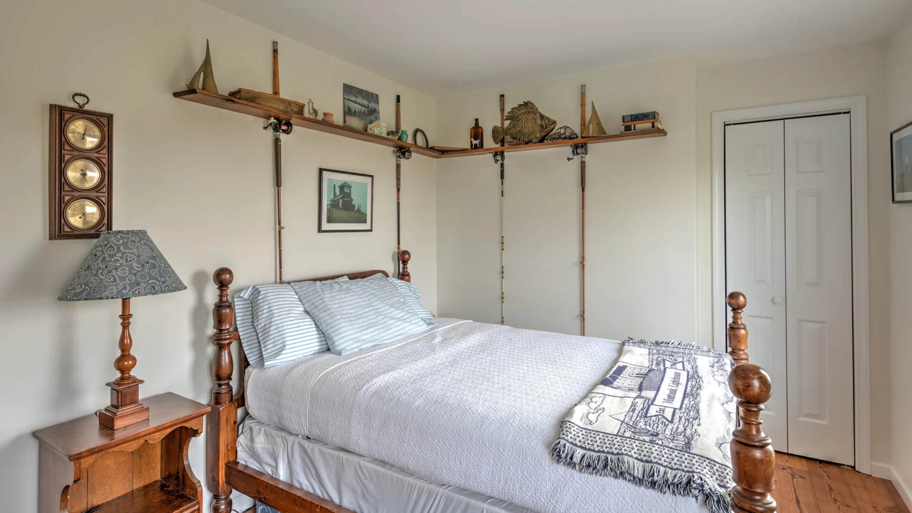 A bedroom with a neatly made bed and wall shelves holding decorative objects.