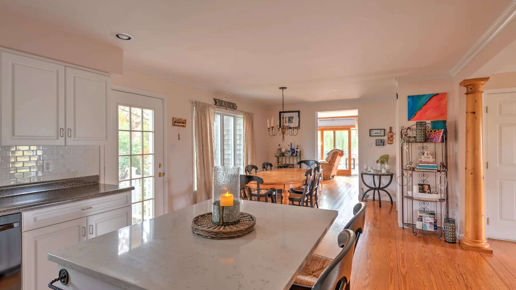 A bright open-plan kitchen and dining area with a large island and a wooden dining table.