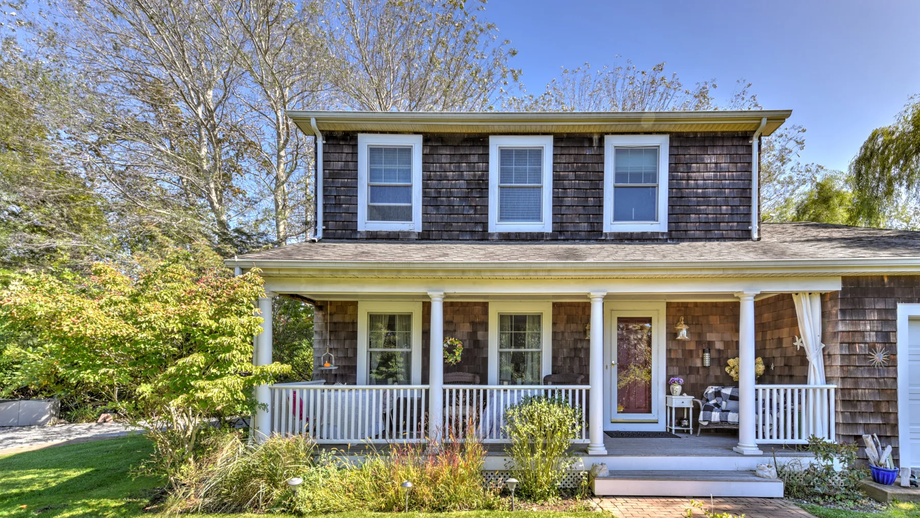 A shingled house with a covered porch and white railing.