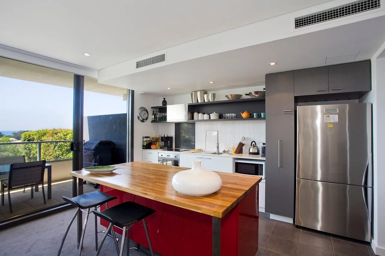 Cocina de planta abierta con una isla central y amplias ventanas con vistas a la vegetación.